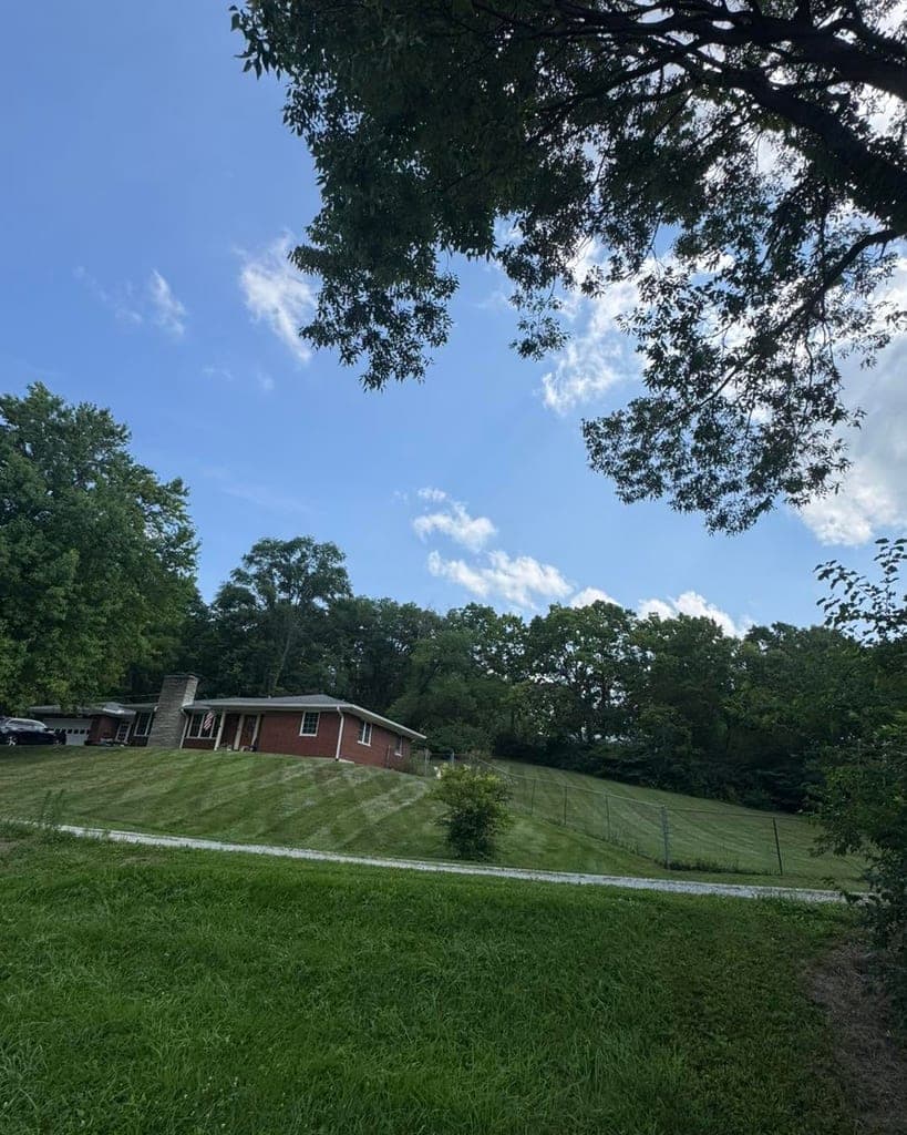 Neatly mowed sloped yard beside a brick ranch home
